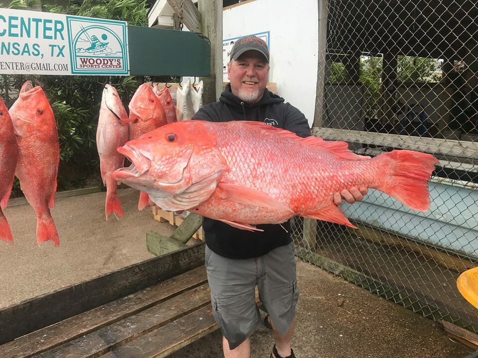 Guy on dock with large red fish